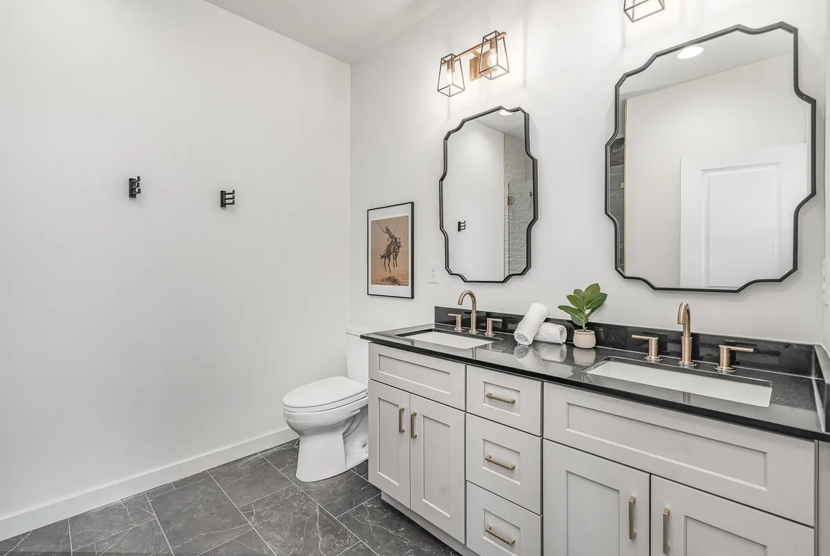 A sophisticated bathroom showcasing dual sinks with modern faucets, expansive mirrors, and contemporary wall art. The tranquil mood is perfect for self-care routines and moments of relaxation.