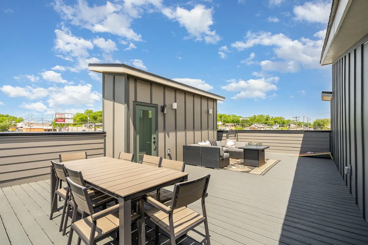 An outdoor dining table and lounge area are set against a backdrop of sky and clouds, evoking the potential for sunset views, stargazing, or daytime barbecues. The space is clearly designed for group gatherings and effortless enjoyment of Nashville's outdoors.