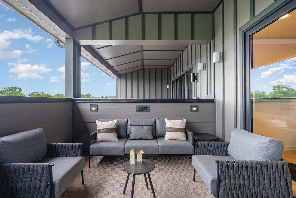 A tranquil exterior seating area featuring comfortable chairs, decorative pillows, and a small coffee table—ideal for sipping refreshments, socializing, or planning your next local adventure.