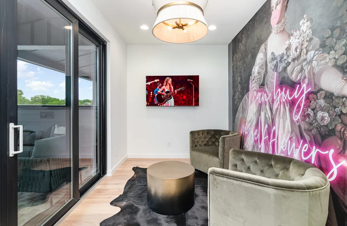 A modern lounge with a striking wall mural of a historical figure, a contemporary television setup, and stylish seating. The space exudes a chic and artistic vibe, encouraging group conversation and immersive viewing experiences.